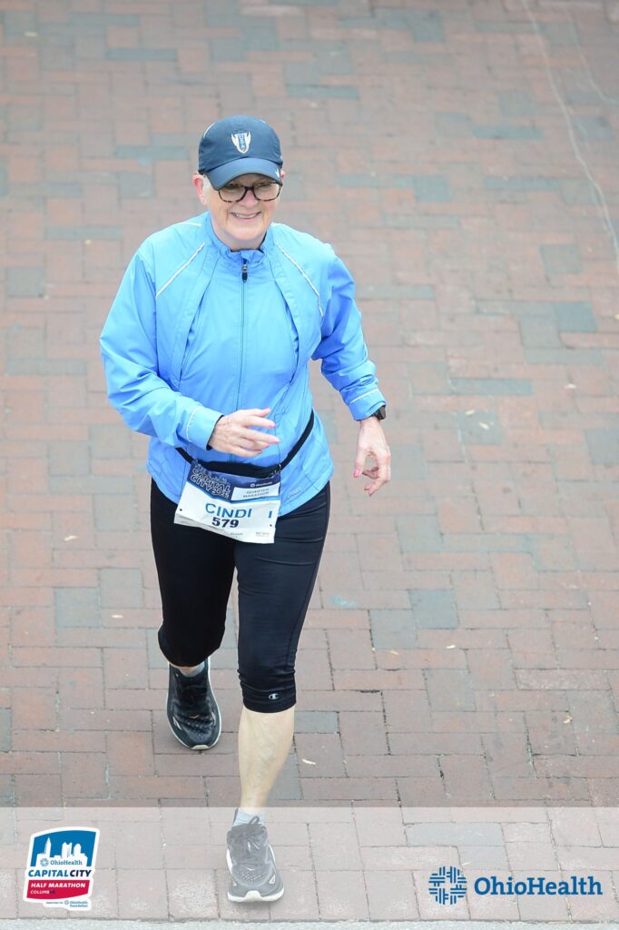 Woman in blue coat and blue hat walking in the Cap City Half Marathon in Columbus, OH.