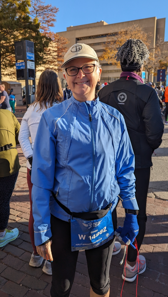 Cindi Leeman standing in a blue coat getting ready to walk the BMW Dallas Half Marathon.